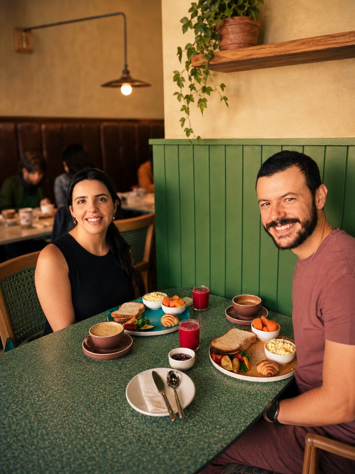 A couple enjoying a breakfast spread of toast, fruit, juice and coffee at Café Vagabond